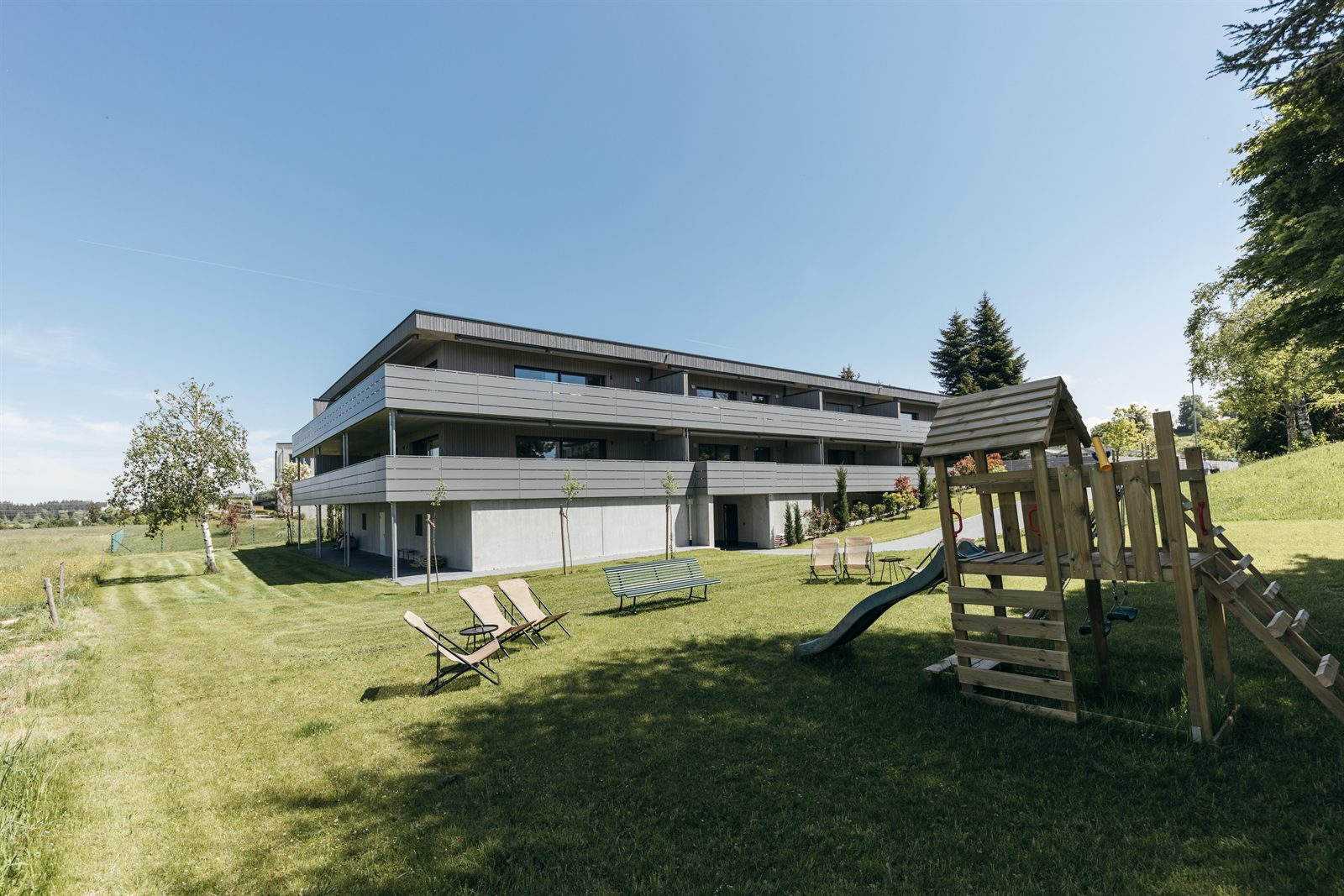Liegewiese mit Spielturm vor dem Haus
